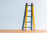 Two pencils creating a shadow of a ladder against a wall