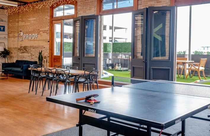 a modern workplace with a meeting table, outdoor space and ping pong table, representing company culture