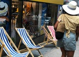 a woman wearing a hat walks past a pop up store advertised by a woman wearing a similar hat